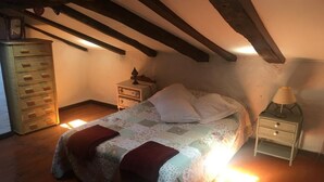 A cozy bedroom with a bed, a nightstand, a dresser, and a lamp. - Casa Rural Luey (luey)