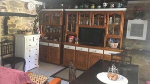 A kitchen with wooden cabinets, a built-in oven, and a television. - Casa Rural Luey (luey)