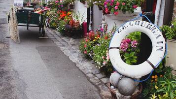 En gata med en rad blomlådor och en livboj med texten ”LES MARINS” på trottoaren.