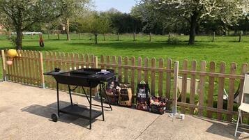 A barbecue grill with charcoal bags and a wooden fence in a park.