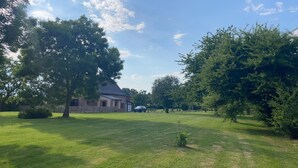 A grassy area with a building and trees.