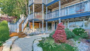 A multi-story building with a covered outdoor area, stone steps, and a variety of plants. - Lakefront View w Private BEACH! - Spacious Luxury Estate Home ~ Pet Friendly (Port Stanley)