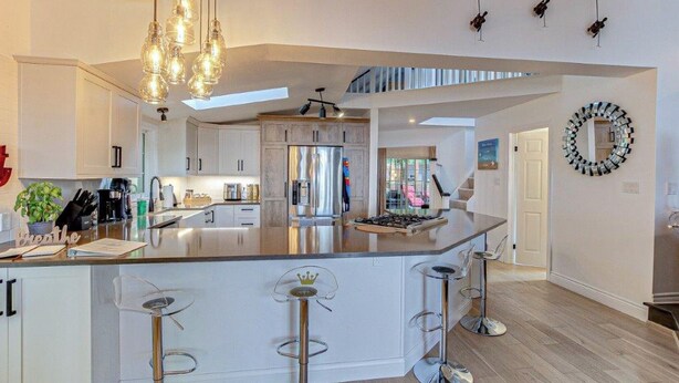 A modern kitchen with a large island, bar stools, and pendant lighting. - Lakefront View w Private BEACH! - Spacious Luxury Estate Home ~ Pet Friendly (Port Stanley)