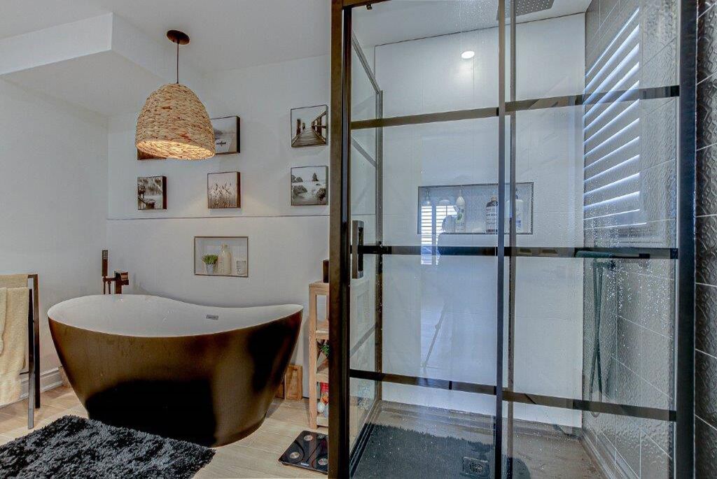 A modern bathroom with a freestanding bathtub, a glass shower enclosure, and a pendant light.