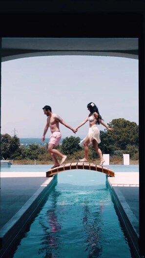 A couple jumping off a pool edge into a swimming pool.