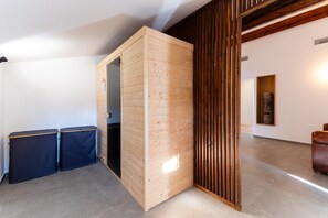 A room with a wooden partition, two trash bins, a brown leather chair, and a framed artwork on the wall.