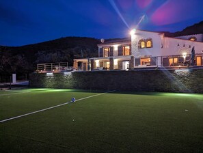 Ein gut beleuchtetes Wohnhaus mit einem Tennisplatz im Vordergrund.