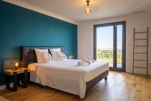 A bedroom with a large bed, two bedside tables, a nightstand, a balcony with a view, and a wooden ladder. - Mas Sureda — Football pitch & indoor/outdoor pools (Argelès-sur-Mer)