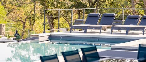 Un área de piscina con sillones de descanso y una barandilla de metal.