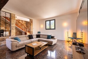 A spacious living area with a large L-shaped sectional sofa, a wooden coffee table, and a stone accent wall. - Mas Sureda — Football pitch & indoor/outdoor pools (Argelès-sur-Mer)