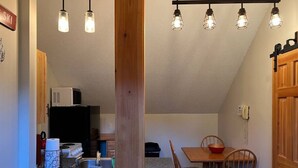 Een keuken met een granieten aanrecht, een houten eettafel met stoelen en hanglampen erboven.