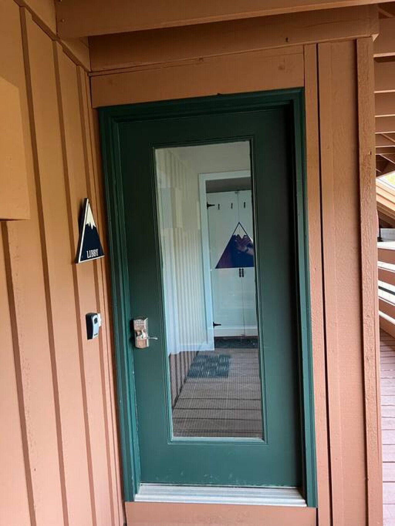 Una puerta verde con una pequeña señal triangular en la pared a la izquierda.