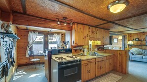 Ein rustikales Blockhaus-Interieur mit einer zentralen Küche, Holzwänden, einem Essbereich und einem gemütlichen Wohnbereich.