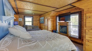 Ein Schlafzimmer einer Holzhütte mit Bett, Kamin und Fenster.