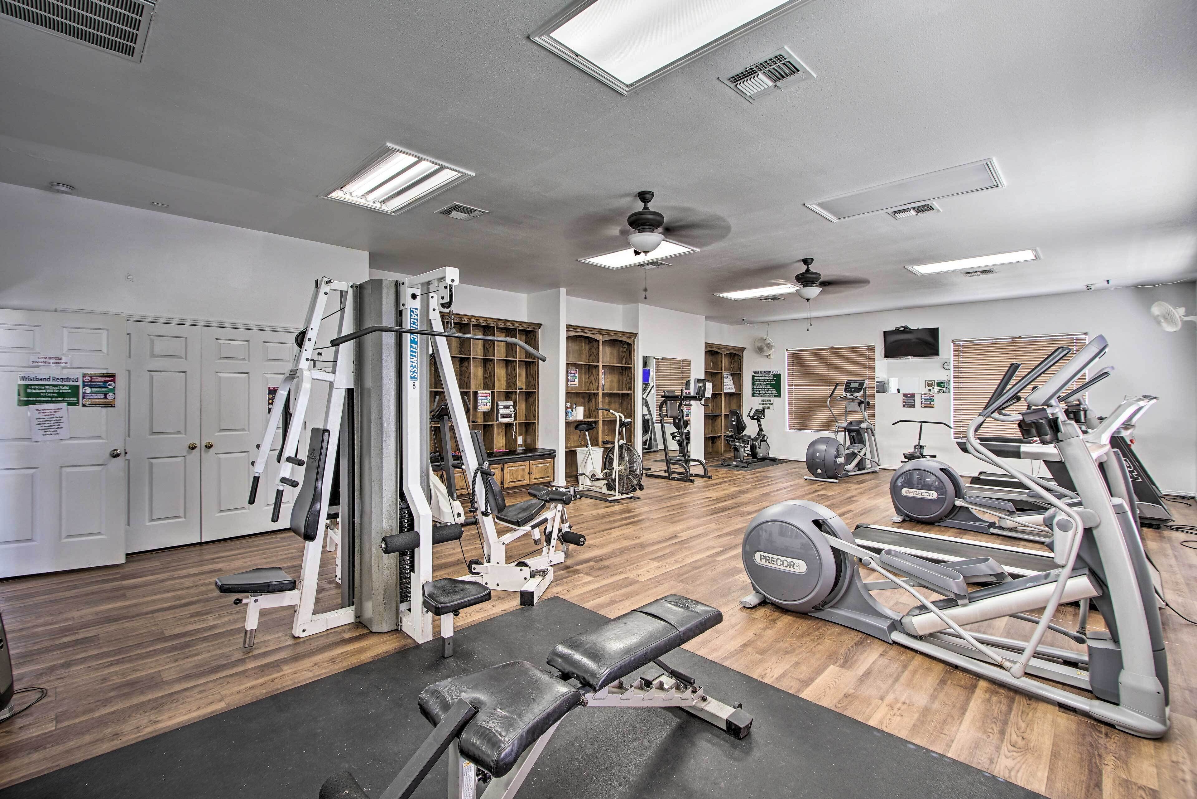 Une salle de sport équipée de divers appareils d’exercice, dotée d’un ventilateur de plafond et d’un plancher en bois.