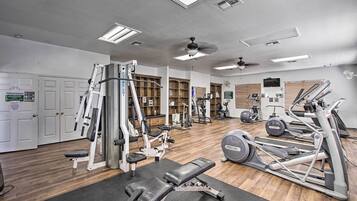 Une salle de sport équipée de divers appareils d’exercice, dotée d’un ventilateur de plafond et d’un plancher en bois.