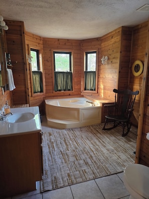 Un baño de cabaña de madera con una bañera, un lavabo y un inodoro.