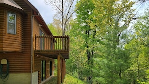 Une cabane en rondins dotée d’un balcon donnant sur une zone boisée.