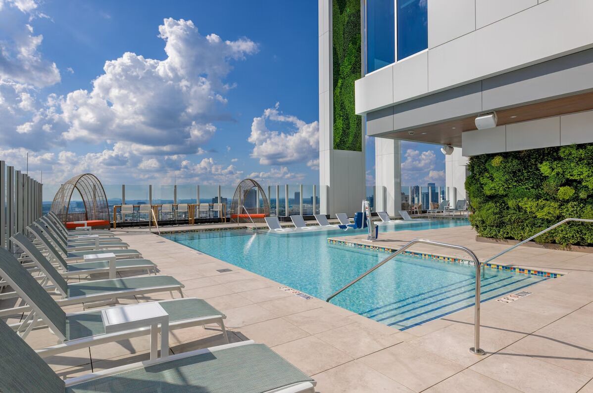 A rooftop pool with lounge chairs and a view of the city skyline.