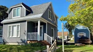 A two-story house with a front porch, a small deck, and a staircase leading to the entrance. - Blue Maple Cottage in Downtown Traverse City (Traverse City)