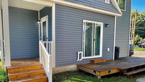 A house with a wooden porch, a sliding glass door, and a small deck. - Blue Maple Cottage in Downtown Traverse City (Traverse City)