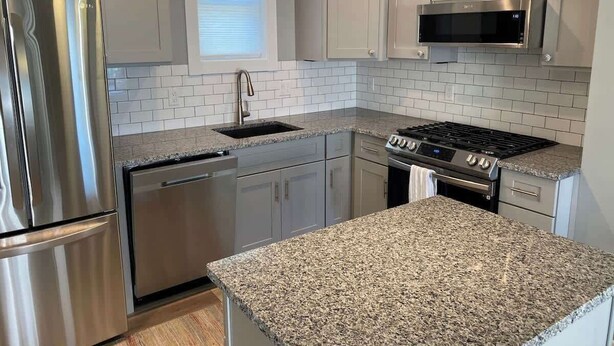 A modern kitchen with stainless steel appliances, granite countertops, and white cabinetry. - Blue Maple Cottage in Downtown Traverse City (Traverse City)