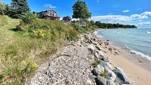 Ein Küsteneigentum mit Strand, felsigem Ufer und einem Haus mit einer Terrasse mit Blick auf das Wasser.