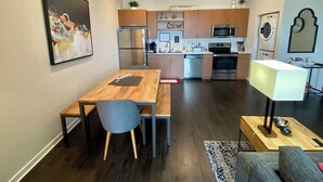 A modern kitchen with wooden cabinets, stainless steel appliances, and a dining area with a wooden table and chairs. - Stylish Traverse City Condo with Balcony (Traverse City)