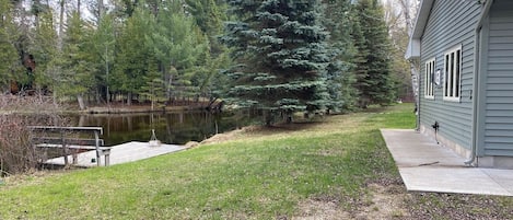 Uma casa com um cais que se estende sobre um lago, cercada por árvores.