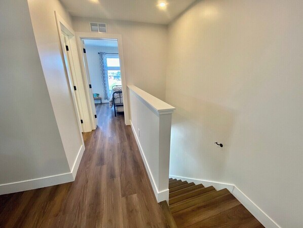 Ein Korridor mit Holzboden und weißen Wänden, der zu einer Treppe führt.