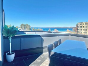 Ein Balkon mit Meerblick, einer Topfpflanze und Gartenmöbeln.