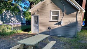 A wooden picnic table in a yard with a small shed in the background. - Convenient 2 Bedroom Home in Traverse City (Traverse City)
