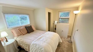 A bedroom with a bed, bedside tables, a lamp, and a window with blinds. - Convenient 2 Bedroom Home in Traverse City (Traverse City)
