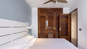 A bedroom with a bed, bedside table, and a ceiling fan.