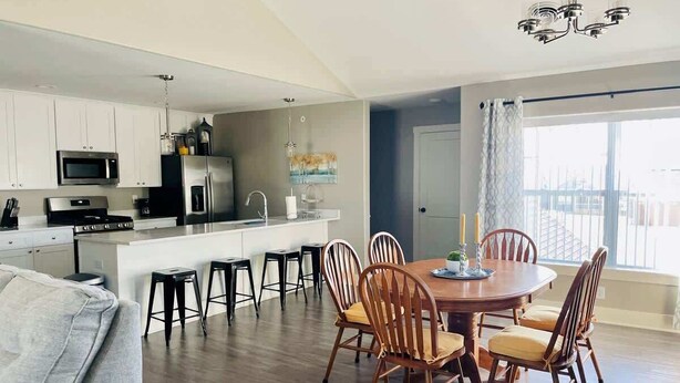 A modern kitchen with white cabinets, a central island, and a dining area with wooden chairs and a table.