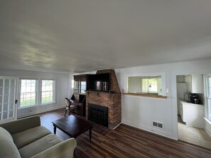 Relax in this inviting living room with a cozy fireplace, comfortable sofa, and large windows.
