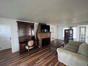 Cozy living space with a brick fireplace, comfortable sofa, and wooden table.