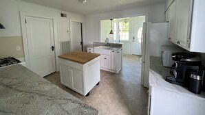 A kitchen with white cabinets, a wooden countertop, a sink, and a stove.
