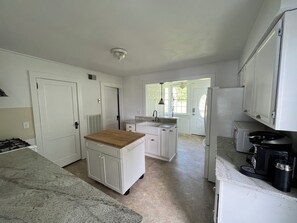 Kitchen features a central island with a sink, gas stove, and coffee maker.