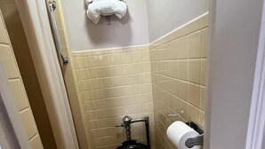 Un baño pequeño con inodoro, toallero y dispensador de papel higiénico.