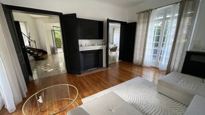 Un salon spacieux avec une cheminée, un canapé et une table basse en verre.