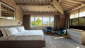 A bedroom with a large bed, a chair, a TV, and a window with a view of a tower.