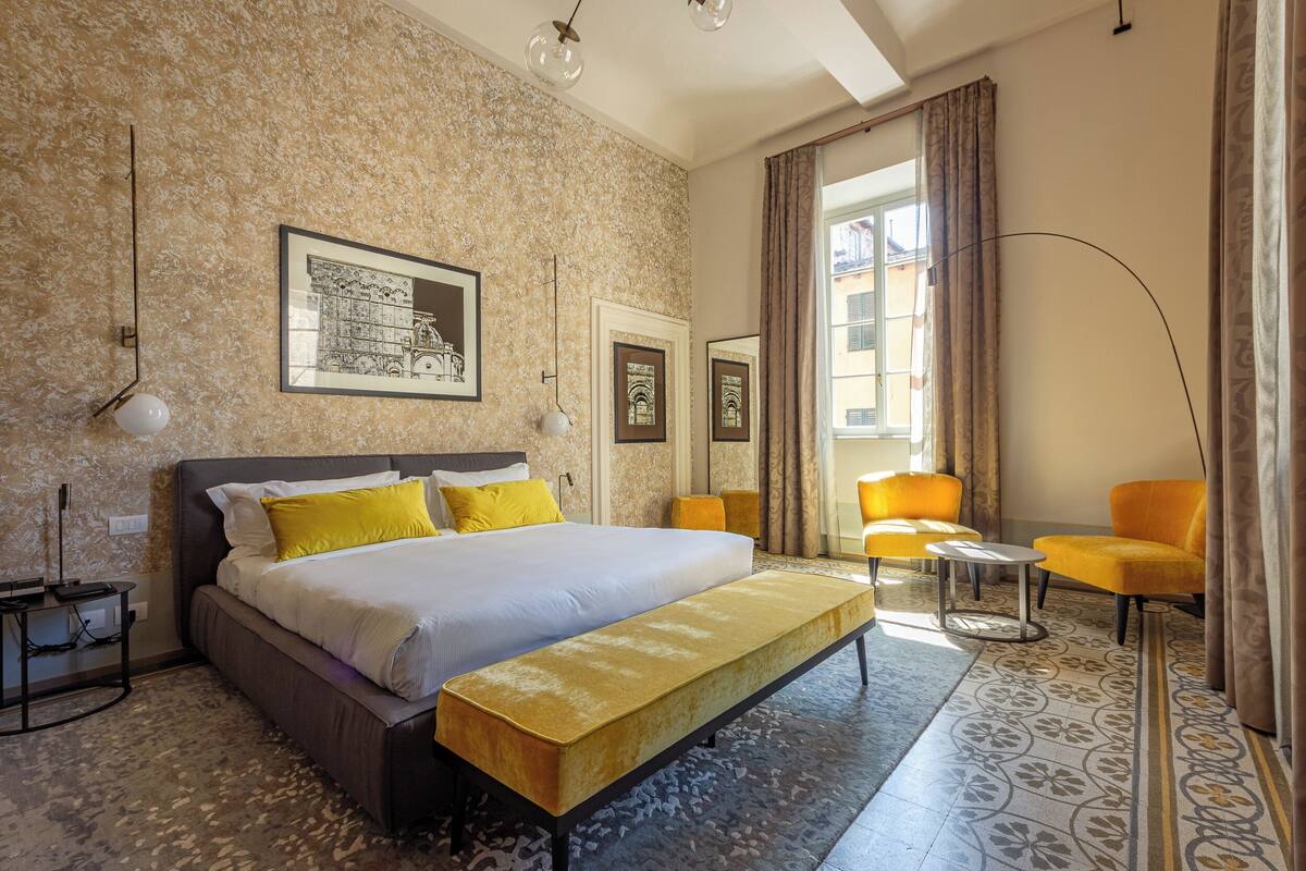 Ein Hotelzimmer mit einem großen Bett, einer Bank, einem Schreibtisch und einem Sessel.