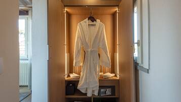 A walk-in closet with a robe hanging on a rack, a telephone, and a radio on the shelves.