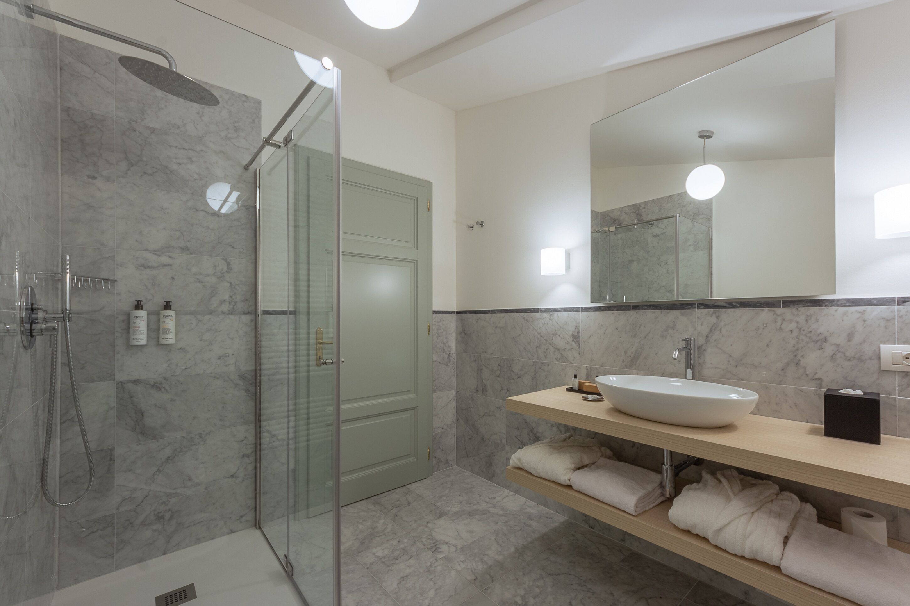 Une salle de bain moderne avec une douche à parois de verre, un grand miroir et un sol carrelé en marbre.