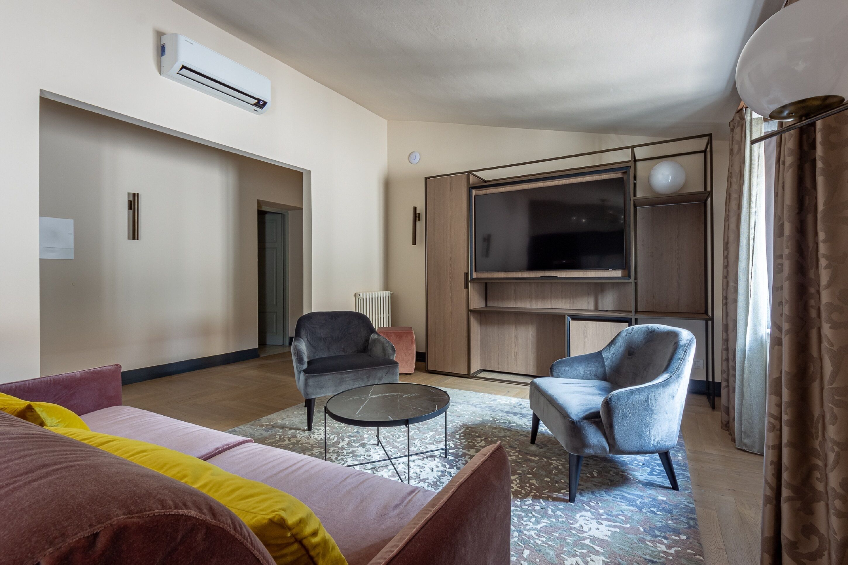 A modern living room with a sofa, armchairs, a coffee table, and a TV.