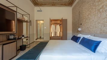 Habitación de hotel con una cama grande, un armario, un escritorio con televisor de pantalla plana y un baño visible a través de una puerta abierta.