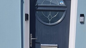Una porta blu scuro con una finestra circolare in vetro, una maniglia in metallo e un piccolo ripiano sopra.