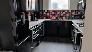 Una cucina compatta con mobili neri, un forno a microonde e un lavandino.