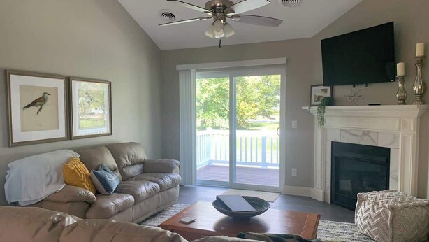 A living room with a sofa, a coffee table, a fireplace, and a sliding glass door leading to a deck. - Bettendorf Condo: 2BR, 2BA, Garage, King master, Pets Welcome! (Bettendorf)